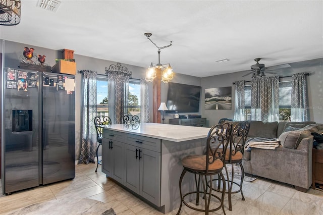 kitchen featuring decorative light fixtures, light tile flooring, ceiling fan with notable chandelier, gray cabinetry, and black fridge