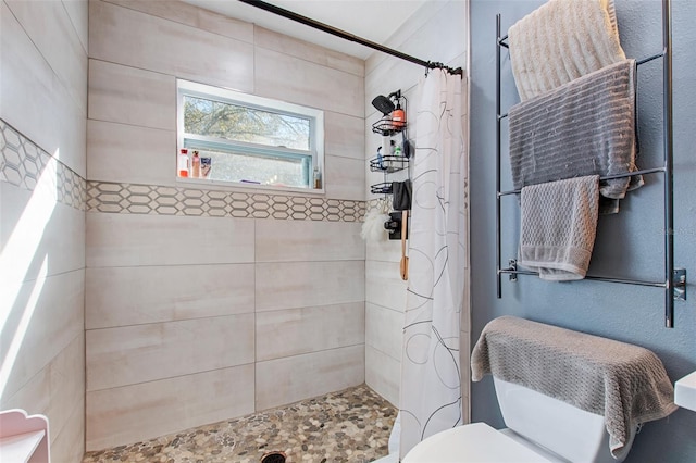 bathroom with a tile shower and toilet