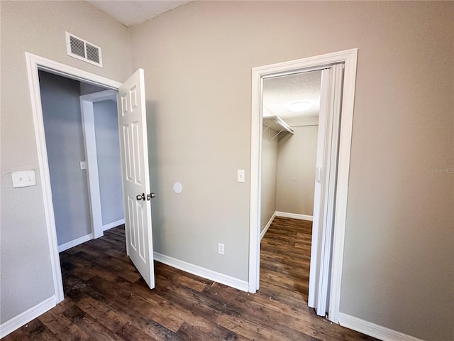 unfurnished bedroom with a spacious closet, a closet, and dark hardwood / wood-style floors