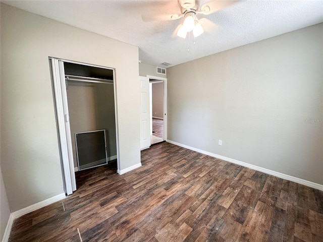 unfurnished bedroom with a textured ceiling, dark hardwood / wood-style flooring, a closet, and ceiling fan