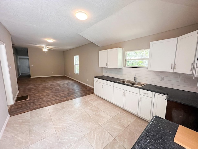 kitchen featuring white cabinets, backsplash, ceiling fan, and sink