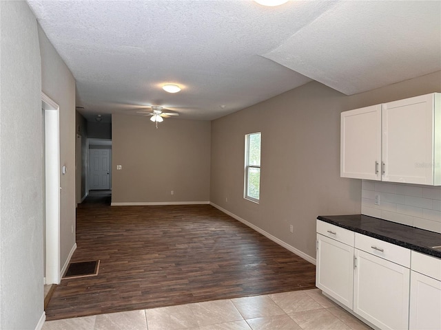 kitchen with white cabinets, a textured ceiling, ceiling fan, and light tile flooring