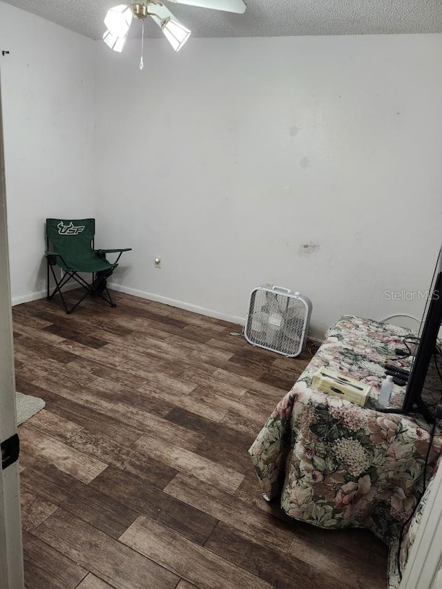 sitting room with a textured ceiling, baseboards, and wood finished floors