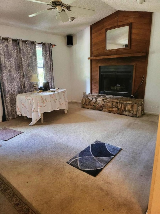 unfurnished living room with carpet floors, a fireplace, lofted ceiling, ceiling fan, and a textured ceiling