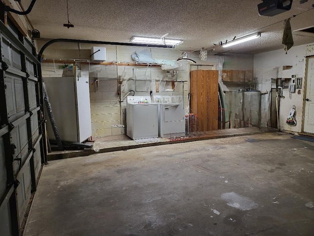 garage featuring a garage door opener, washer and dryer, and concrete block wall