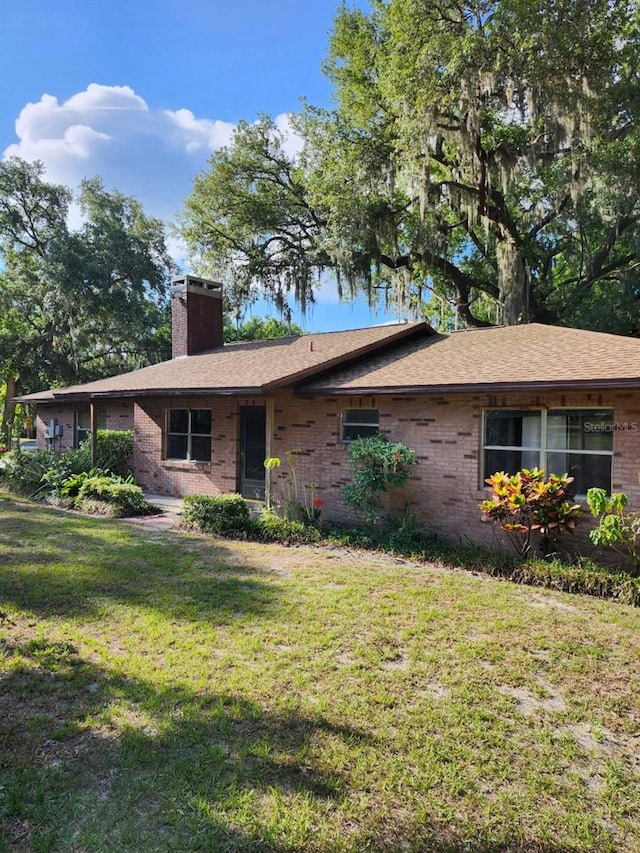 4450 Old Berkley Rd, Auburndale, FL 33823 - ranch-style house featuring a chimney, brick siding, and a front lawn