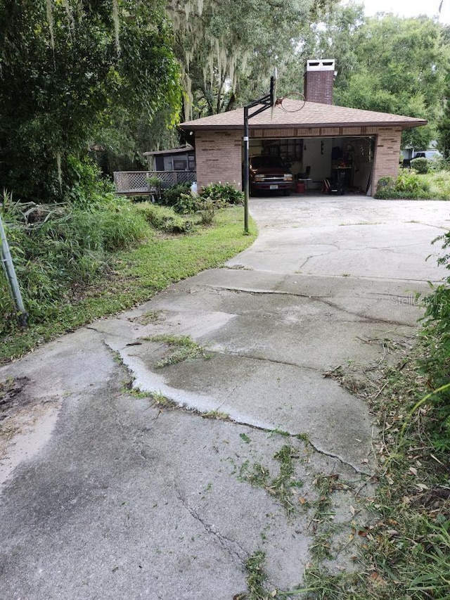 4450 Old Berkley Rd, Auburndale, FL 33823 - view of side of home featuring concrete driveway, a chimney, and a carport