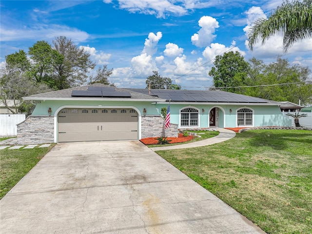 ranch-style home featuring a garage, a front yard, and solar panels