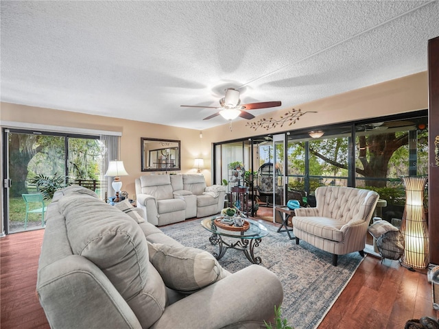 living room with ceiling fan, a textured ceiling, and dark hardwood / wood-style flooring