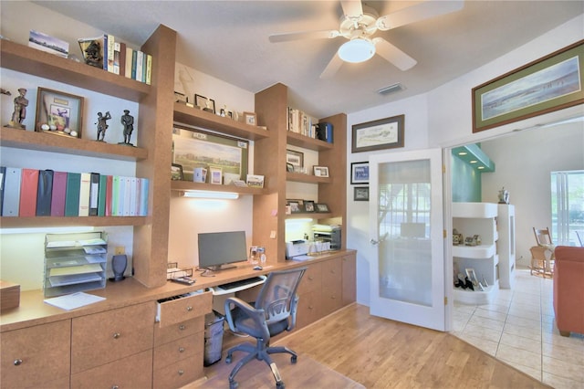 office space featuring light tile flooring, built in desk, and ceiling fan