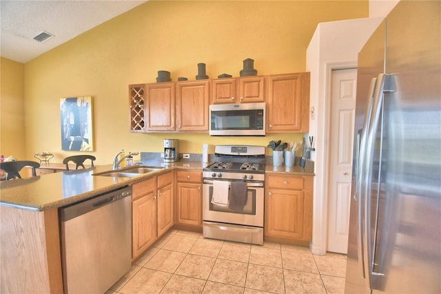 kitchen featuring kitchen peninsula, lofted ceiling, appliances with stainless steel finishes, sink, and light tile floors