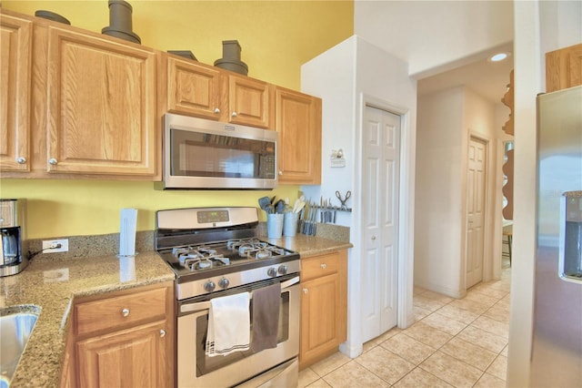 kitchen featuring light tile floors, appliances with stainless steel finishes, and light stone counters