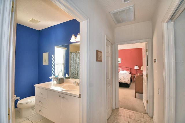 bathroom with toilet, vanity, and tile flooring