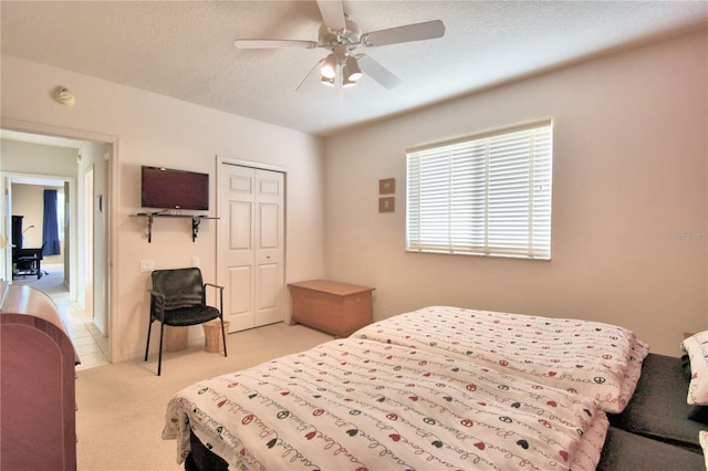 bedroom with light carpet, a closet, ceiling fan, and a textured ceiling