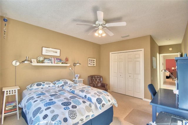 bedroom featuring light colored carpet, a closet, ceiling fan, and a textured ceiling