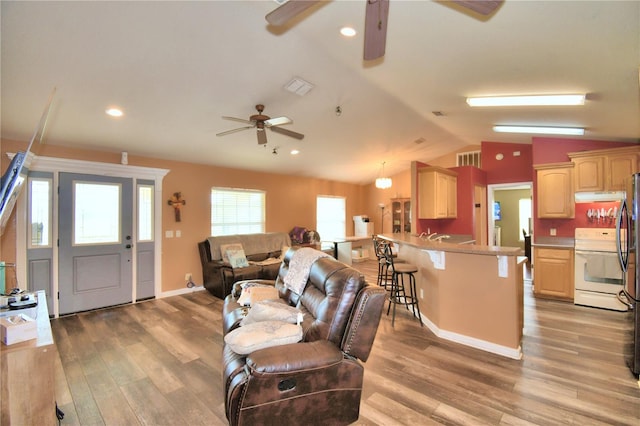 living room with light wood-type flooring, vaulted ceiling, and ceiling fan