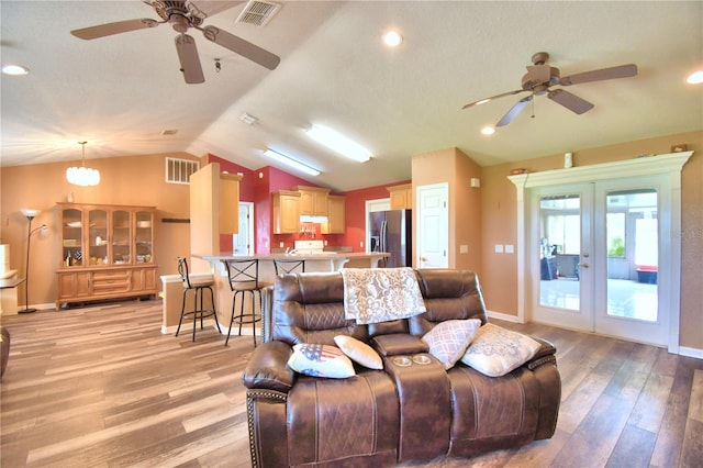 living room featuring vaulted ceiling, light wood-type flooring, a textured ceiling, ceiling fan, and french doors