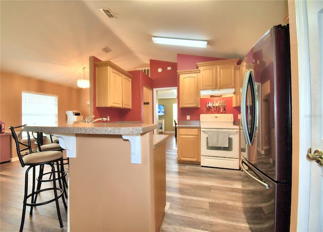 kitchen with vaulted ceiling, stainless steel refrigerator, a kitchen breakfast bar, white electric stove, and light brown cabinetry