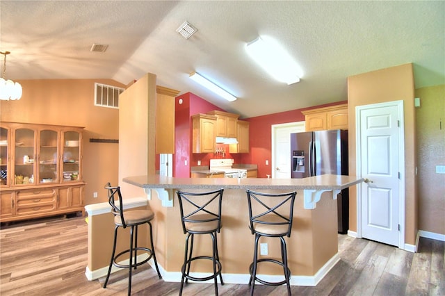 kitchen with a kitchen bar, white range, kitchen peninsula, and lofted ceiling