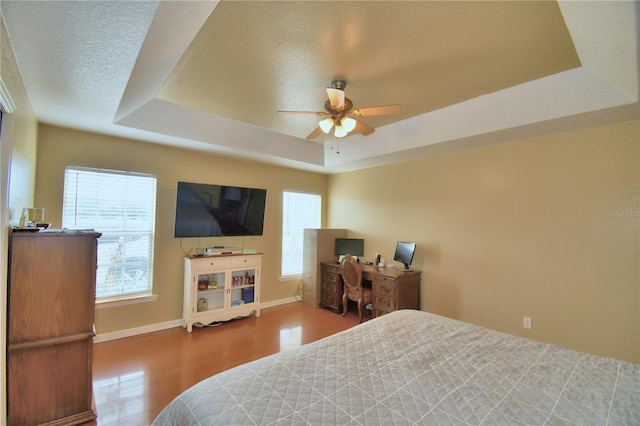 bedroom with a textured ceiling, a raised ceiling, ceiling fan, and hardwood / wood-style flooring