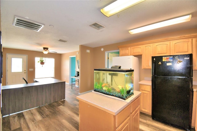 kitchen featuring ceiling fan, black fridge, light brown cabinets, and hardwood / wood-style floors