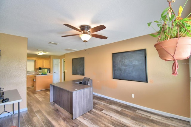 interior space with ceiling fan, light brown cabinets, dark wood-type flooring, and a center island