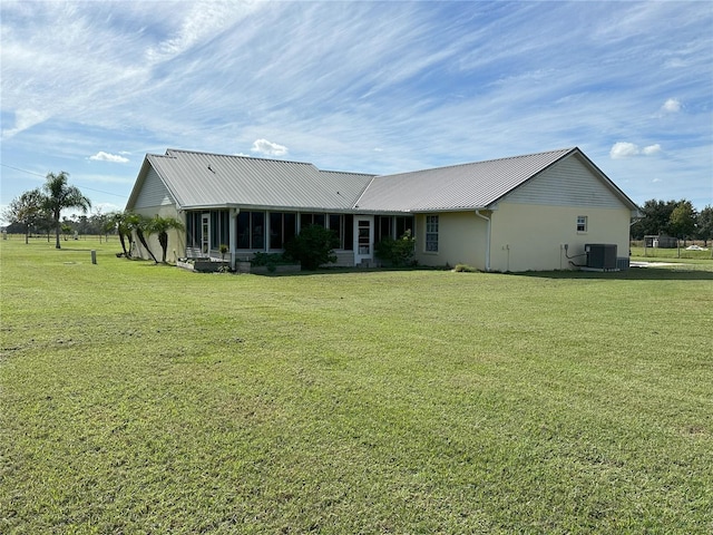 back of property featuring a lawn, a sunroom, and central AC unit