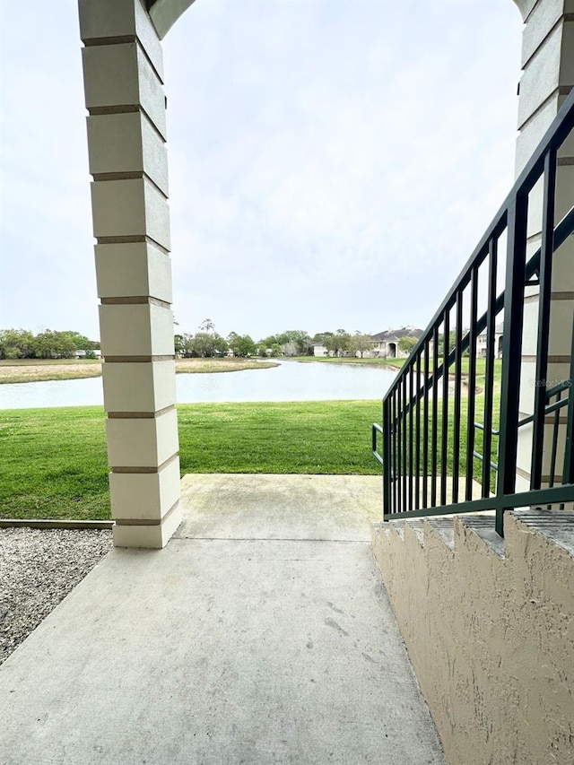 view of gate featuring a water view, a yard, and a patio