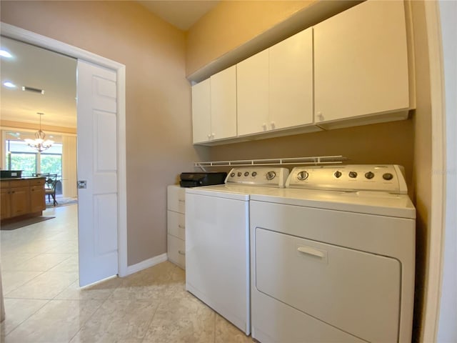 laundry area with a notable chandelier, washing machine and dryer, light tile patterned floors, and cabinets