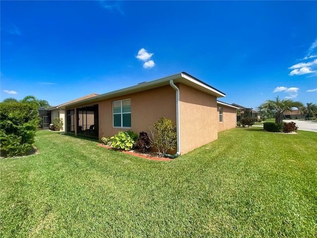 view of side of property featuring a sunroom and a lawn