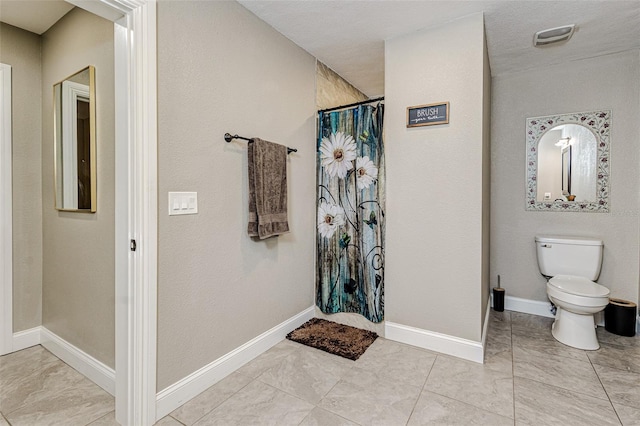 bathroom with toilet, a textured ceiling, and tile flooring