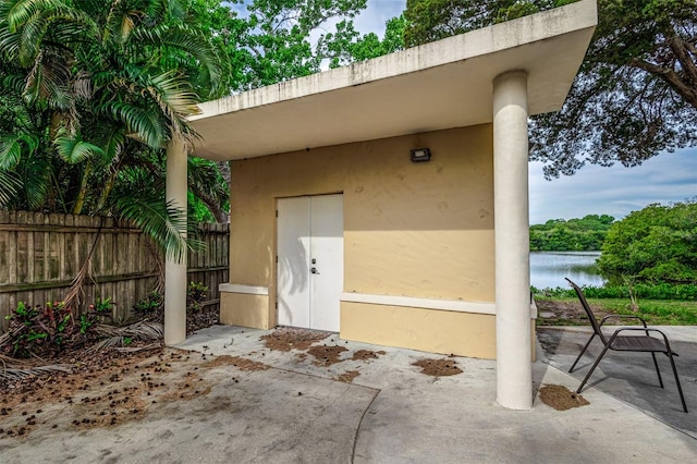 view of exterior entry with a water view and a patio area