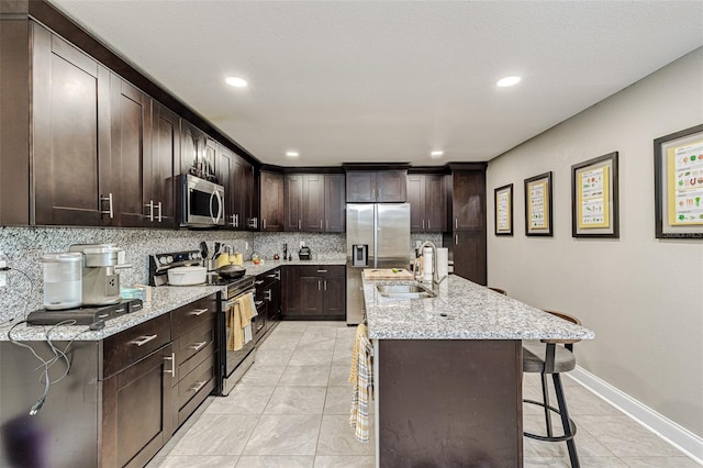 kitchen with a breakfast bar, stainless steel appliances, tasteful backsplash, and light stone counters