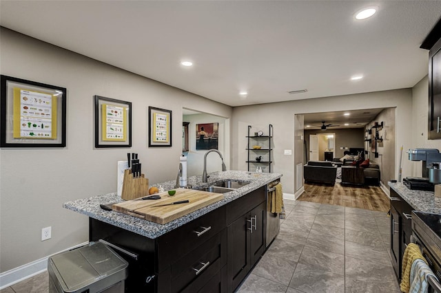 kitchen featuring light tile floors, dishwasher, sink, ceiling fan, and an island with sink