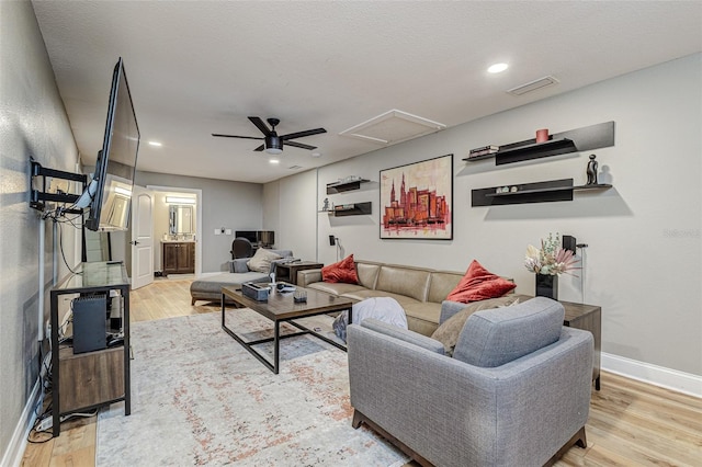 living room featuring a textured ceiling, ceiling fan, and light wood-type flooring