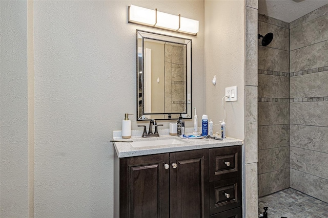 bathroom featuring tiled shower and large vanity