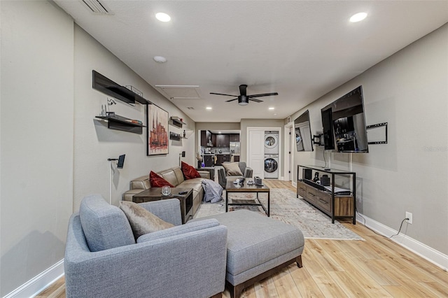 living room featuring ceiling fan, light wood-type flooring, and stacked washing maching and dryer