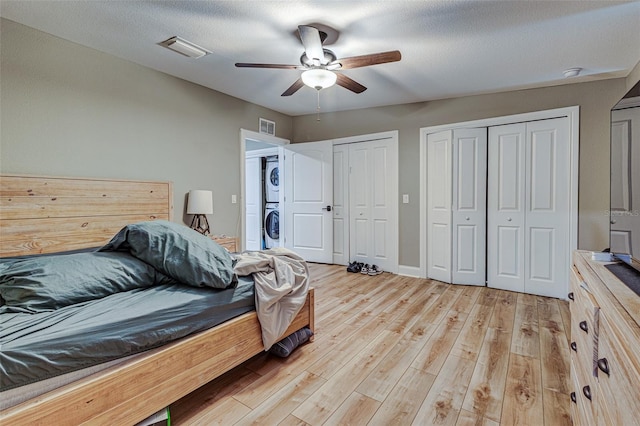 bedroom featuring light hardwood / wood-style flooring, ceiling fan, stacked washer and dryer, and a textured ceiling