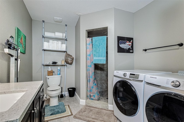 laundry area featuring light tile floors, washing machine and dryer, and sink