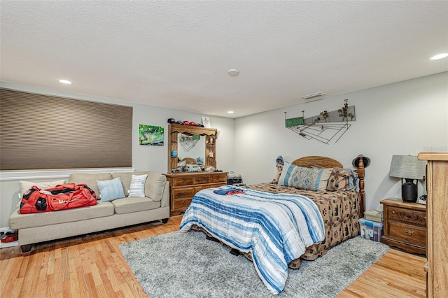 bedroom featuring a textured ceiling and light hardwood / wood-style flooring