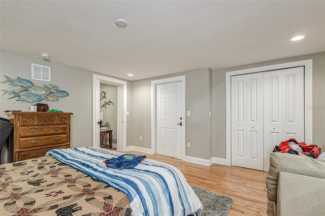 bedroom featuring a closet, light wood-type flooring, and a textured ceiling