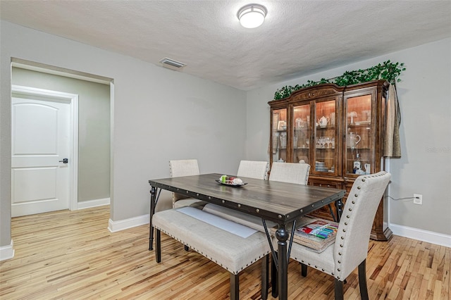 dining room with light hardwood / wood-style floors and a textured ceiling