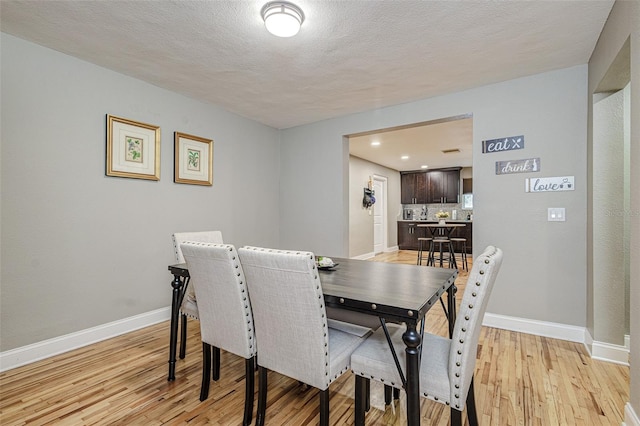 dining room with light hardwood / wood-style flooring and a textured ceiling