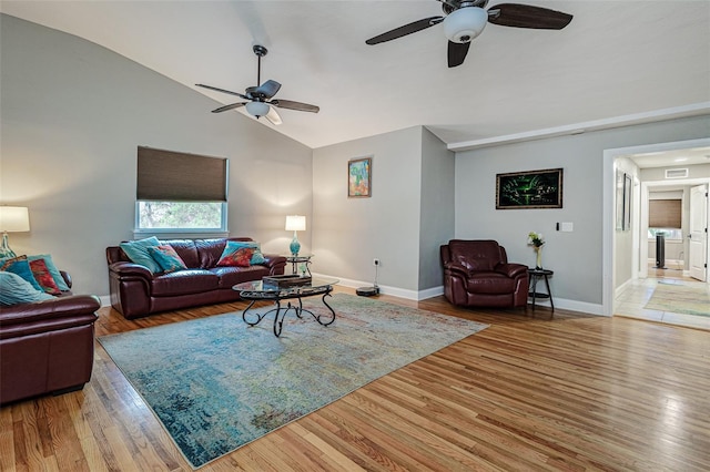 living room featuring ceiling fan, lofted ceiling, and light wood-type flooring