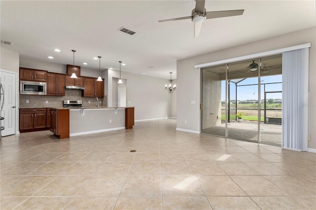 kitchen with decorative light fixtures, stainless steel microwave, ceiling fan with notable chandelier, a kitchen breakfast bar, and stove