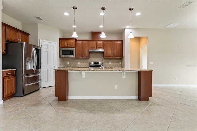 kitchen featuring hanging light fixtures, light stone countertops, a kitchen breakfast bar, and appliances with stainless steel finishes