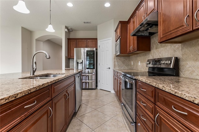 kitchen with appliances with stainless steel finishes, hanging light fixtures, backsplash, and wall chimney range hood