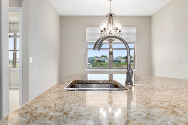 kitchen with a healthy amount of sunlight, light stone countertops, and a notable chandelier