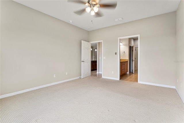 unfurnished bedroom featuring light colored carpet, ensuite bath, and ceiling fan