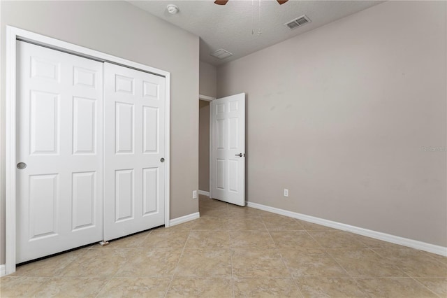 unfurnished bedroom with light tile flooring, a closet, ceiling fan, and a textured ceiling